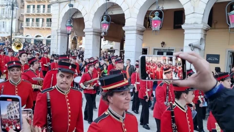Philharmonic marching band in red uniforms parading under the historical Liston Stock Footage 334639020