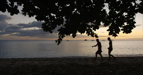 Philippines - Sunset on the beach. A couple walking by in silhouette. Stock Footage 58936699