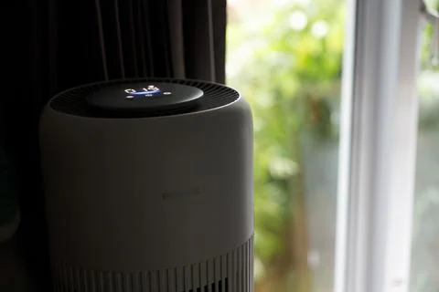 Philips air purifier placed on windowsill with black curtains beside it Stock Photos