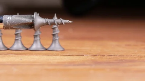 The Phillips screwdriver and black screws are on a wooden table. Moving camera Stock Footage 73393391