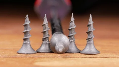 The Phillips screwdriver and black screws are on a wooden table. Moving camera Stock Footage