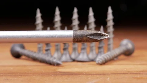 The Phillips screwdriver and black screws are on a wooden table. Moving camera Video stock 73394290