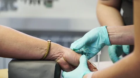 Phlebotomist technician drawing blood from arm of a patient with needle and Stock Footage