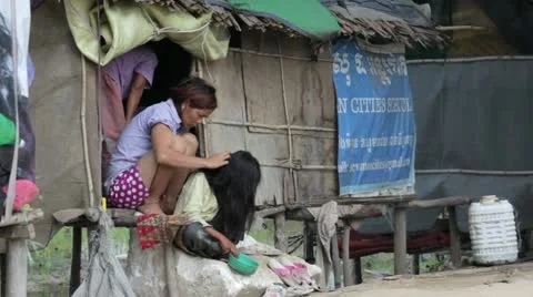 PHNOM PENH SLUMS - JUNE 2012: mother removing louse from daugther Stock Footage 12178592
