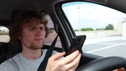 Phone addicted driver compulsively checks his smartphone while driving in traffi Stock Footage 343720429