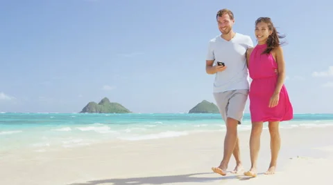 Phone app - Couple on beach using smartphone walking and laughing outdoors Stock Footage 60685807