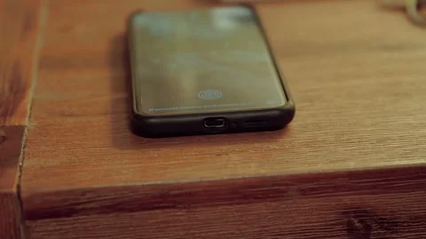 A phone on a bedside table is unplugged from charge and picked up Video stock 249819006