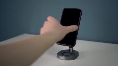 A phone with a black screen is placed on a magnetic stand with wireless charging Stock Footage 314465397