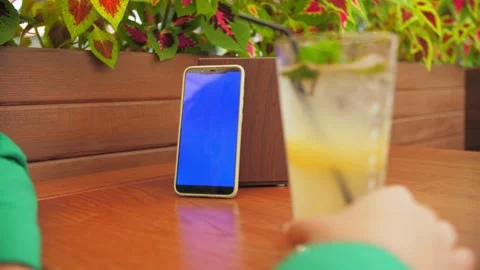  Phone with a blue screen stands on a table in a restaurant.People use the p Stock Footage 203508856