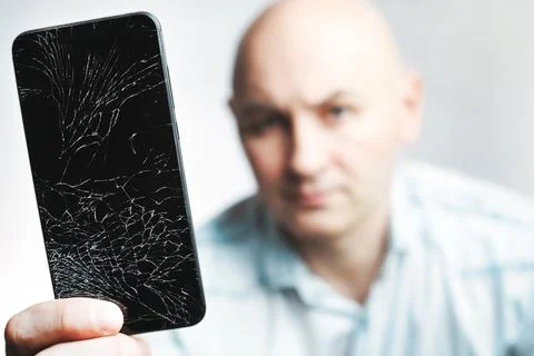 Phone With A broken screen close-up. A white man is holding a black smartphone Stock Photos