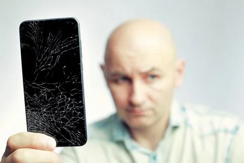 Phone With A broken screen close-up. A white man is holding a black smartphone Foto stock