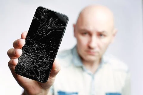 Phone With A broken screen close-up. A white man is holding a black smartphone Foto stock