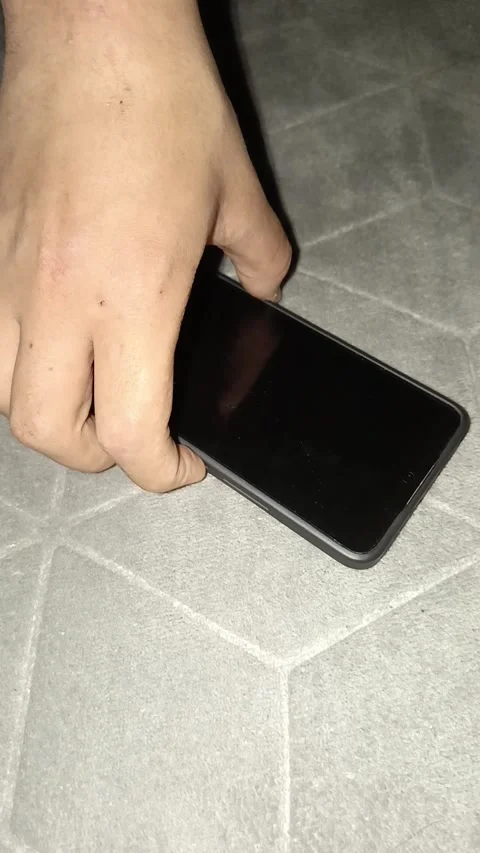 The phone is charged via a cable. A mans hand checks the charging of the phone Stock Footage 314360124