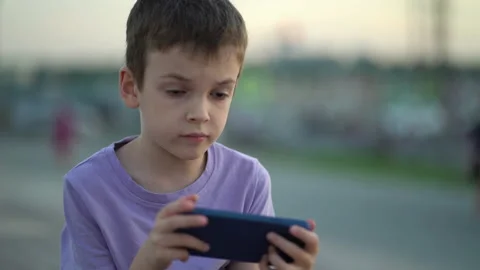 Phone dependency. The boy enjoys playing on the phone Stock Footage 206179623