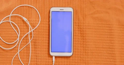 Phone with empty screen and earphones on orange fabric Stock Footage 161849252