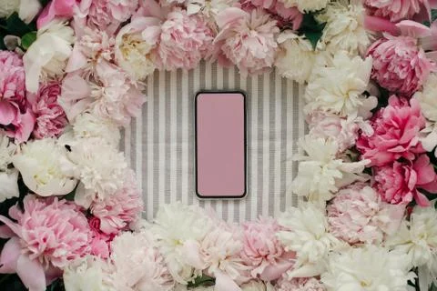 Phone with empty screen and peonies frame flat lay on rustic table cloth. Spa Stock Photos