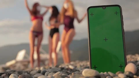 Phone with a green screen and tracking dots on the beach, three multi-racial Stock Footage 140142495