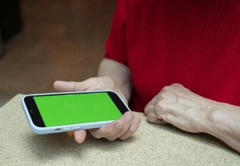 Phone with a green screen in the arm of an elderly woman of retirement age. Stock Photos