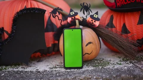 Phone with a green screen on the background of Halloween props, bats, pumpkins Stock Footage 250410038