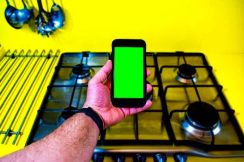 Phone with green screen with the background of a kitchen. Stock Photos