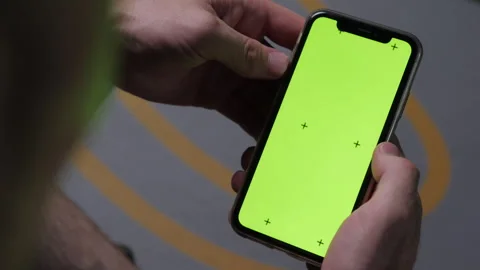 A phone with a green screen is held in a hand 库存影片 312064374