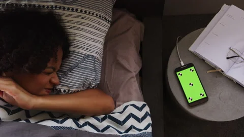 Phone with a green screen on the table next to a sleeping woman Stock Footage 264219525