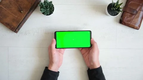 Phone with green screen on the table with notebook and purse view from top Stock Footage 156728924