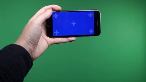 Phone in the hand close up isolated at green background. Phone screen is blue Stock Footage 102760765