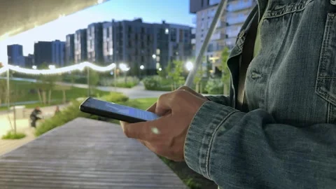 Phone held steady, a man drafts a text message beneath a canopy in a modern.. Stock-Footage 341513683