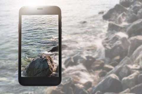 Phone layout on background of clear waters and a rocky beach Stock Photos