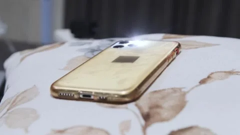 Phone lying on bed surface flashing during an incoming call, close-up of modern 스톡 동영상 333581244