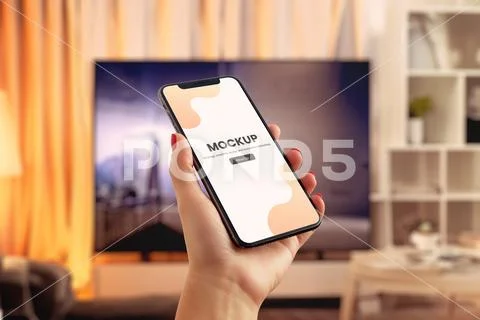 Phone mockup in hand front of TV PSD 템플릿