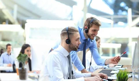 Phone operator working at call centre office helping hiss colleague. Stock Photos