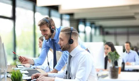 Phone operator working at call centre office helping hiss colleague. Foto stock
