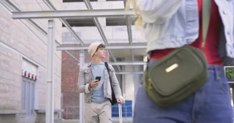 Phone pinging, man checking map while walking metal walkway, pulling suitcase, Stock Footage 336897132