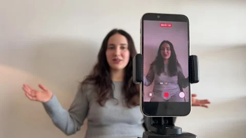 Phone screen in focus with influencer blurred in the background Stock Footage 328102268