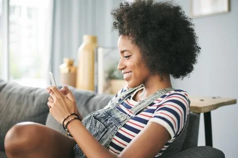 Phone, smile and text message with woman on sofa in living room of home for Stock Photos