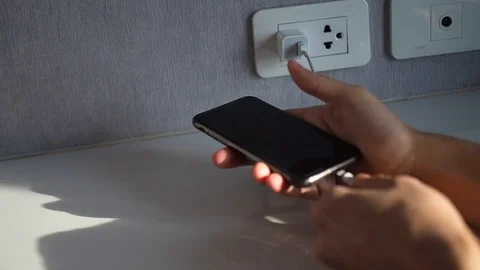 Phone user plugs in Apple iPhone to charge the battery Stock Footage