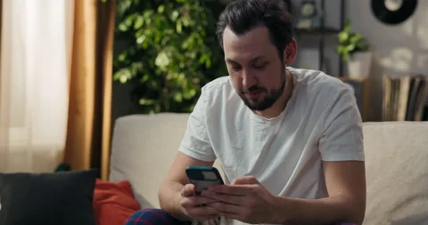 A phone user reading a text message on a screen, relaxing on the couch at home Stock Footage 218277848