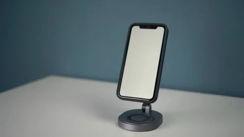 A phone with a white screen is placed on a magnetic stand with wireless charging Stock Footage 314465520