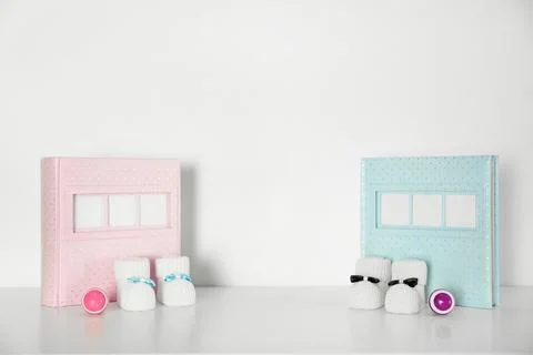 Photo albums with bootees and rattles for baby room interior on table near wh Stock Photos