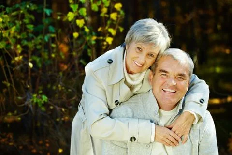 Photo of amorous aged man and woman looking at camera in autumnal park Stock Photos