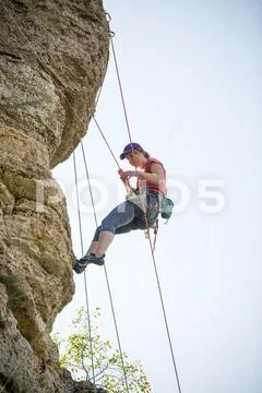 Photo of athlete woman in helmet clambering over rock Stock Photos