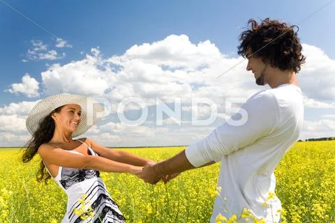 Photo of attractive couple holding by hands and whirling on the meadow at leisur Stock Photos