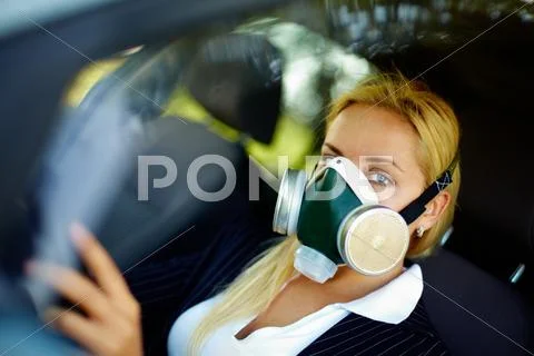 Photo of blond female breathing through respirator while driving in polluted are Stock Photos