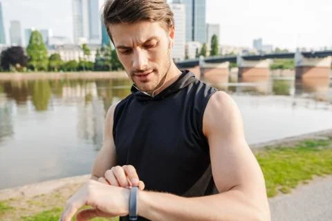 Photo of brooding caucasian man using stopwatch while working out on city riv Stock Photos