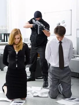 Photo of business co-workers standing on knees being aimed at by evil terrorist Фото