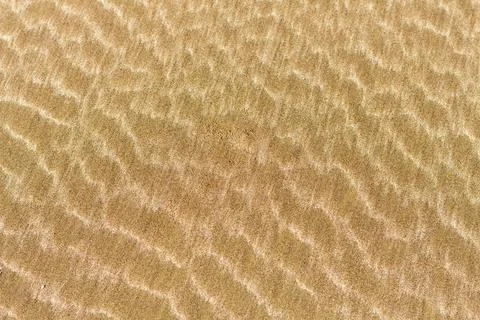 Photo capturing an abstract sand pattern created by the sea waves, showcasing Stock Photos
