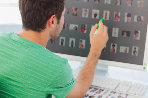 Photo editor pointing at his screen with a green marker Stock Photos