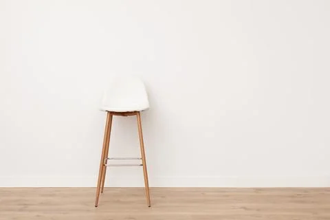 Photo of an empty bar stool standing in front of a white wall. Stock Photos